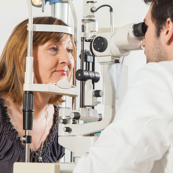 Ophthalmologist examining a middle-aged female patient using a slit lamp in an eye clinic.