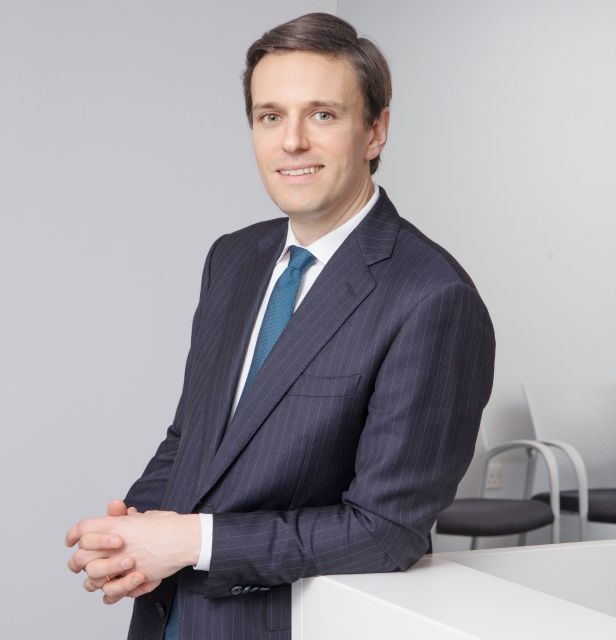 Mr James E. Neffendorf professional headshot leaning against table smiling