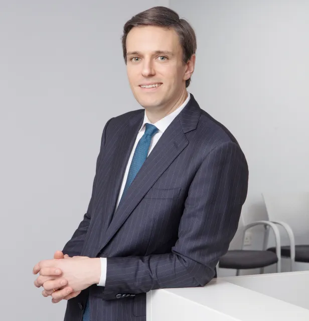 Mr James E. Neffendorf professional headshot leaning against table smiling